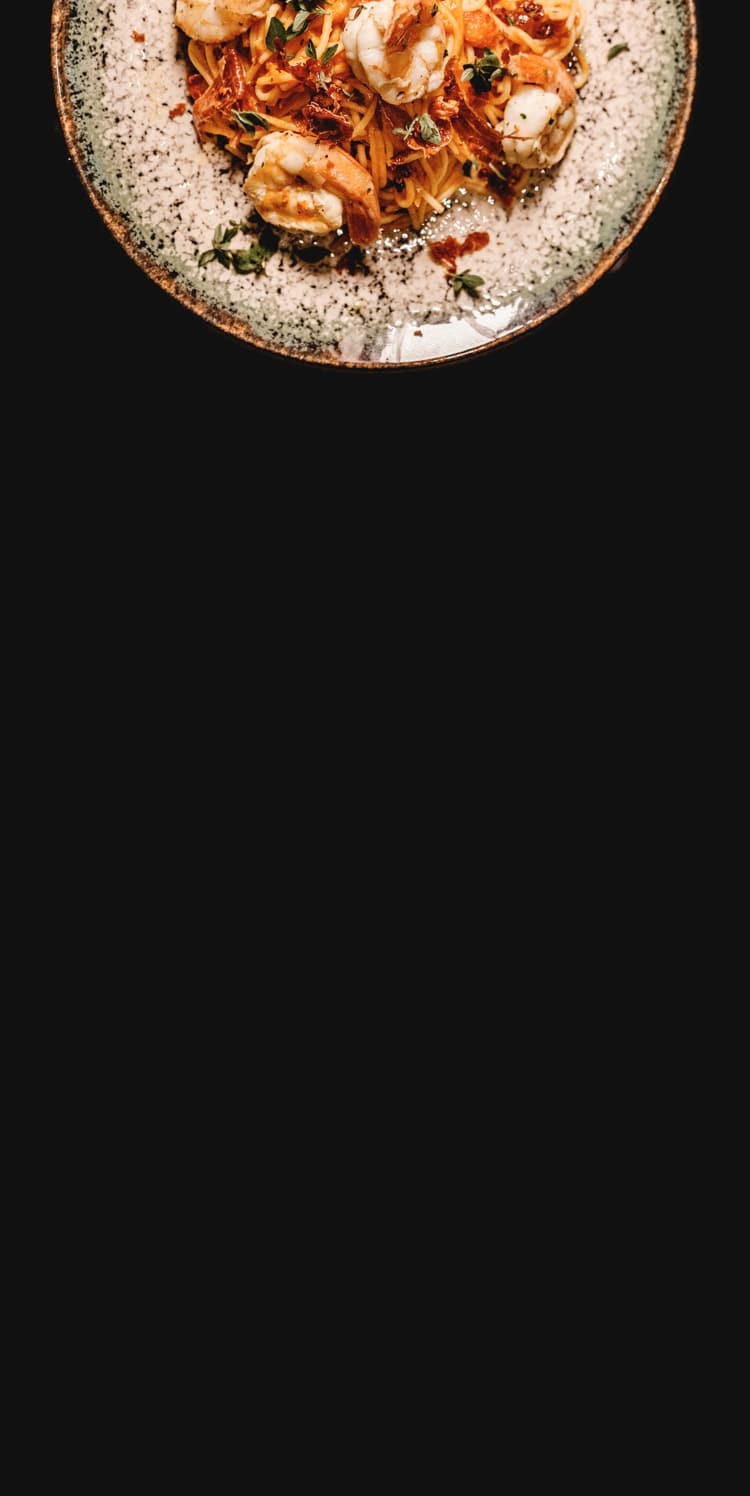 Close-up of a plate of spaghetti with shrimp, sun-dried tomatoes and herbs.