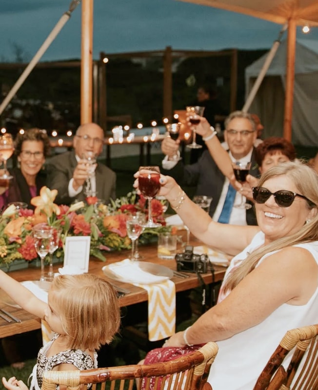 group of people toasting with wine glasses at an outdoor event
